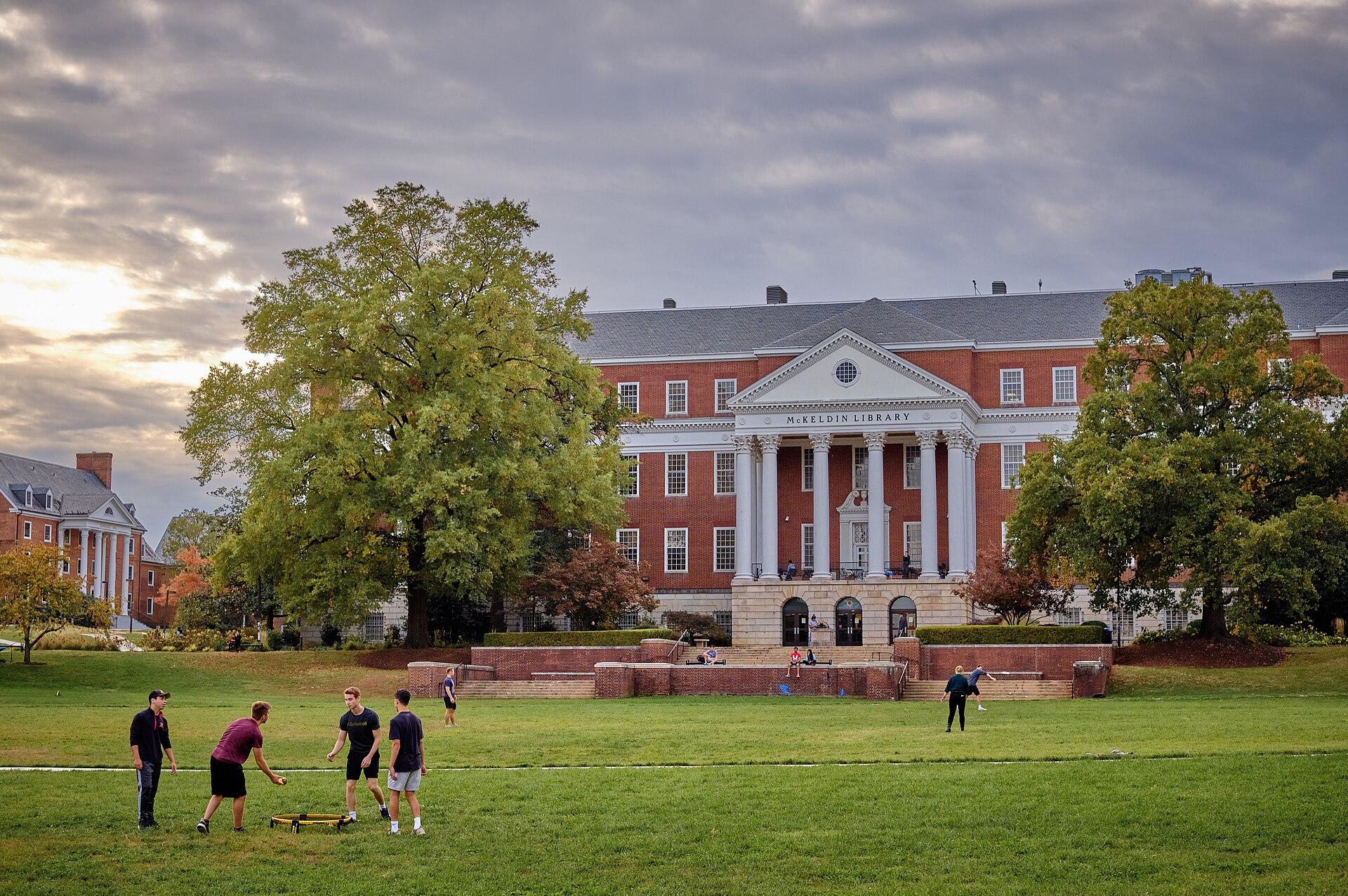 A broad green campus mall leads to a columned library building.