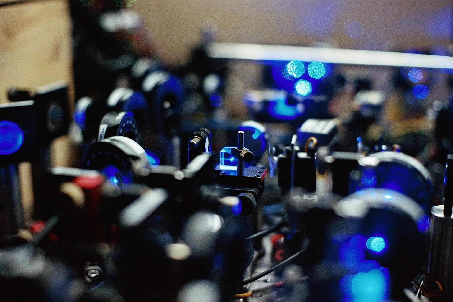 Blue laser light passes through optical components on a laboratory table.