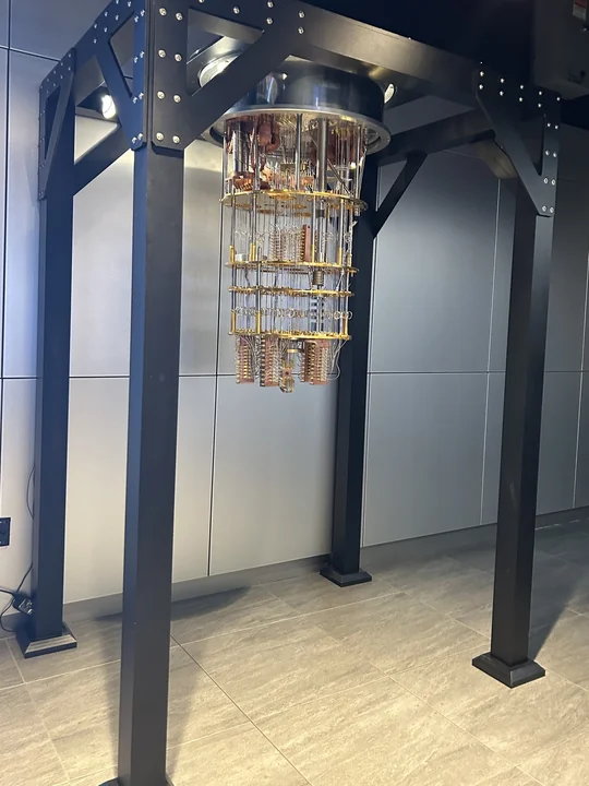 A gold-colored quantum-computing refrigeration assembly hangs within a tall black support frame at IBM’s Think Lab.