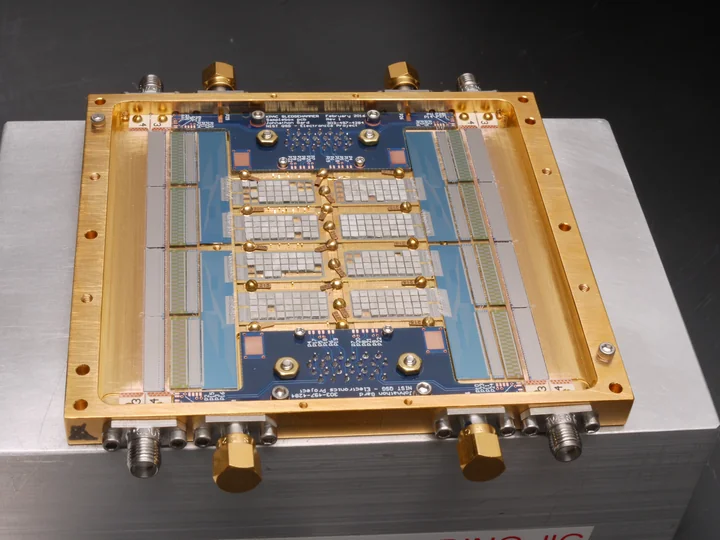 A rectangular array of small detector elements and fine wiring mounted on a circuit board inside a gold-colored metal frame.
