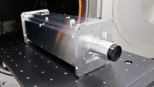 The assembled silver quantum-photonic payload enclosure on a laboratory optical table before launch.