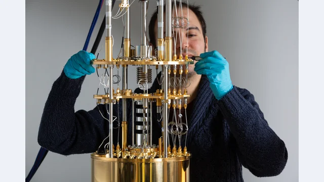 A researcher works beside the wiring and metal stages of a cryostat in the QCMX Quantum Circuits and Matter laboratory at École Polytechnique.