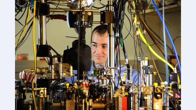 NIST researcher David Leibrandt with a quantum logic clock in October 2013. This archival photograph shows a different clock and experiment from JILA’s 2022 strontium-cloud redshift measurement.