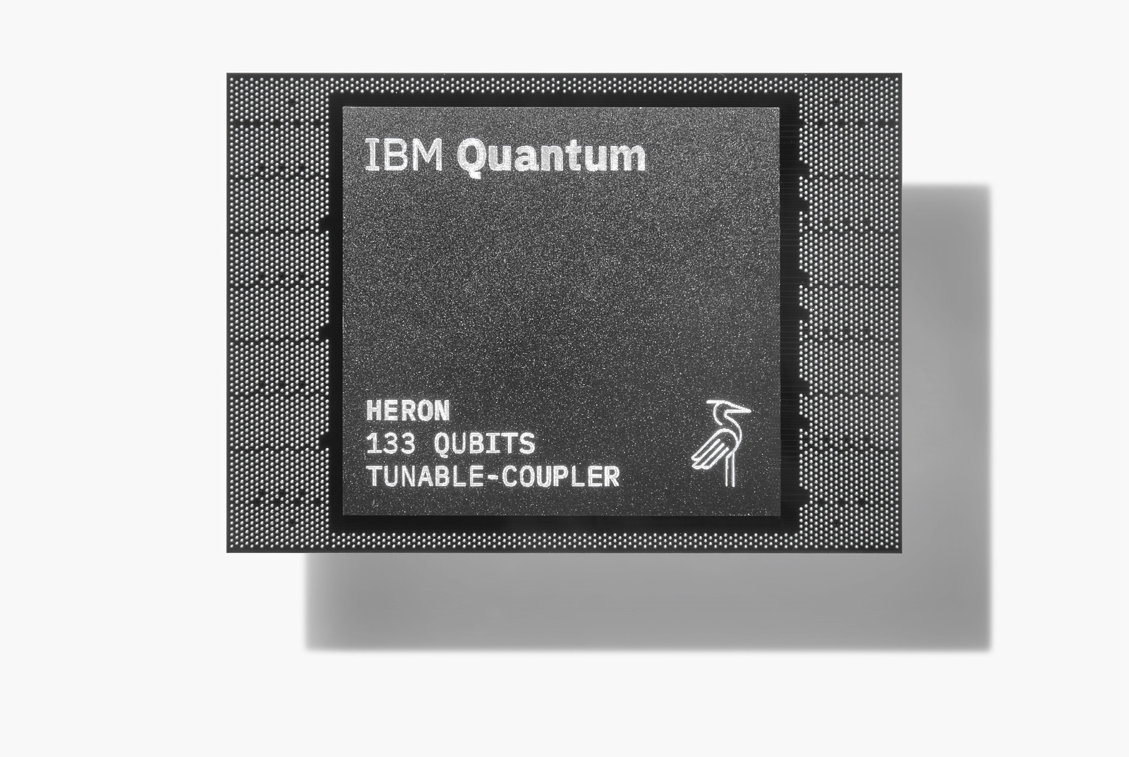 A real IBM Heron quantum processor photographed on a pale surface, marked 133 qubits