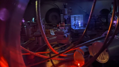 Laser light illuminates a vacuum chamber and optical equipment in JILA’s nuclear-clock laboratory