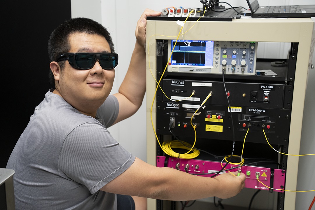 Researcher beside racks of equipment used in quantum-networking research at NIST.