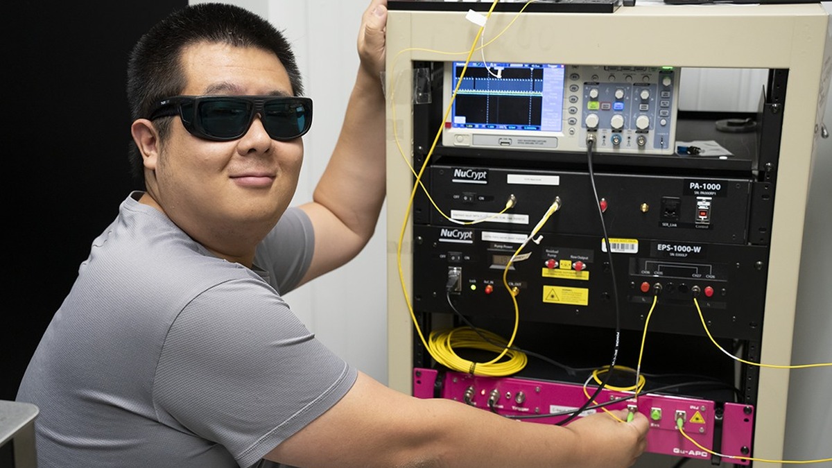 Researcher beside racks of equipment used in quantum-networking research at NIST.