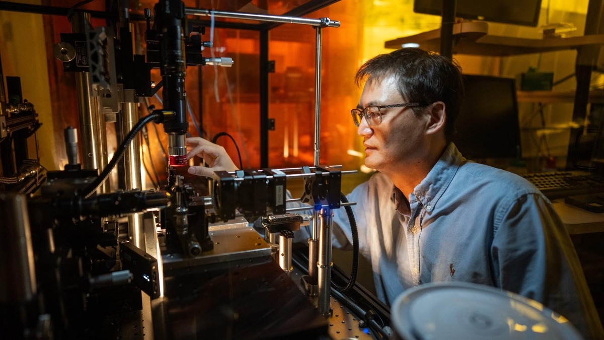 Researcher beside optical equipment and laser components in Sandia’s nanofiber laboratory.