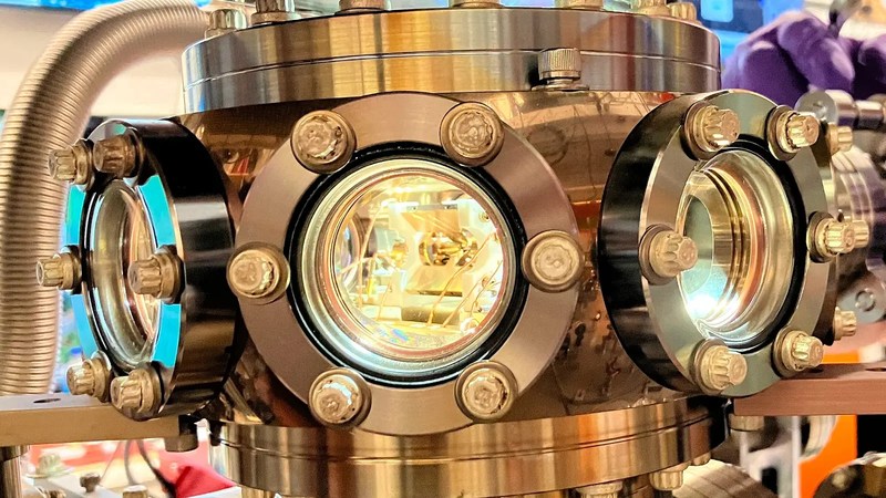 Metal vacuum chamber with glass viewports surrounding a linear Paul ion trap.