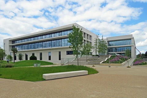 The Ray Dolby Centre in Cambridge, with a white facade, broad steps and landscaped grounds, photographed in May 2024.