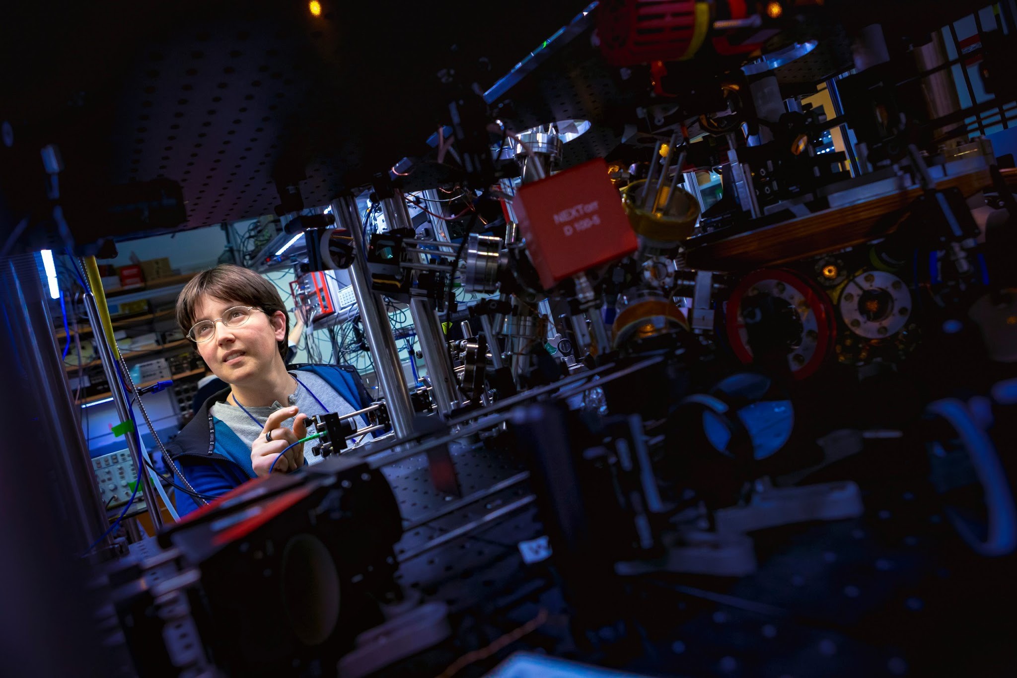 A researcher stands beside optical and electronic apparatus in a waveguide-cavity laboratory.