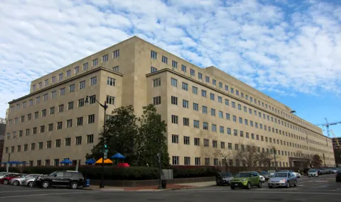 The long limestone facade of the Government Accountability Office headquarters in Washington, D.C., seen from a street corner.