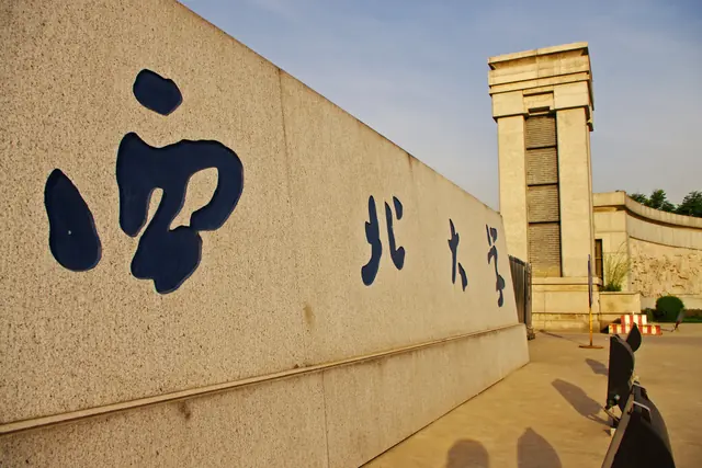 Chinese characters naming Northwest University on a stone wall beside the Chang'an campus entrance tower.