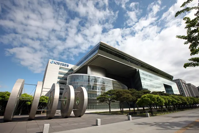 Korea Development Bank headquarters with its KDB sign, glass-fronted entrance and sculpture in the foreground.