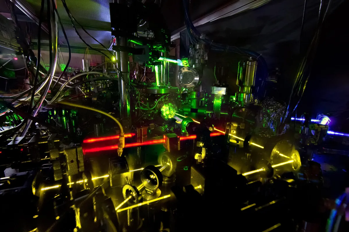 Laser beams and optical equipment surround an atomic-clock apparatus.