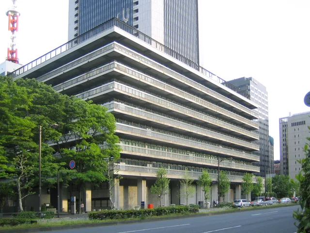 The NTT Communications headquarters building stands behind trees along a Tokyo street.