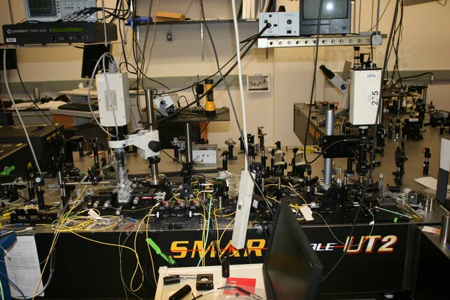An optical bench is covered with mirrors, mounts, cables and laboratory instruments.