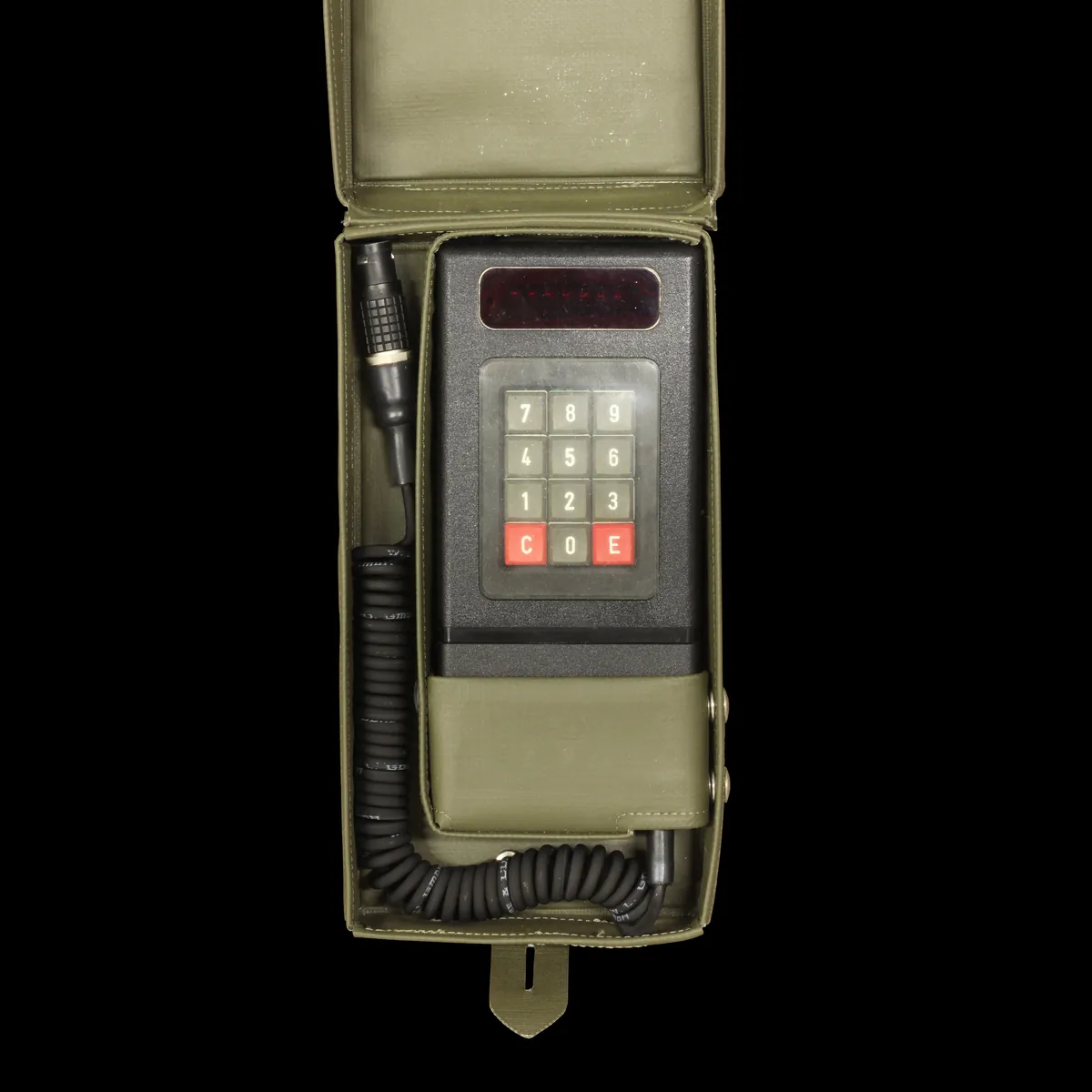 A historic handheld cryptographic device with a keypad and coiled cable.