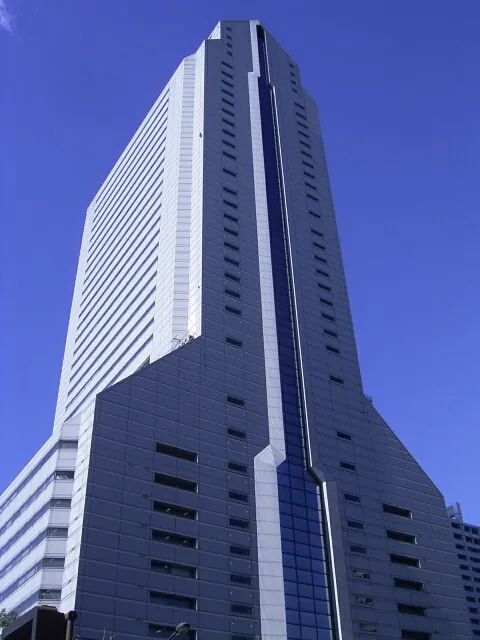 The tall NEC Super Tower rises against a blue sky in Tokyo.