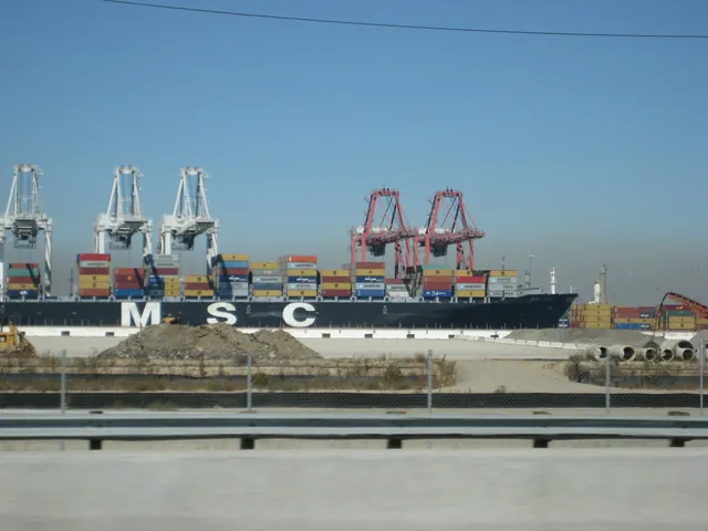 A container ship and loading cranes line a terminal at the Port of Long Beach.