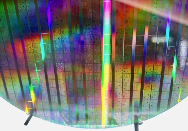 A circular Intel wafer reflects rainbow colours across rows of quantum-computing chips.