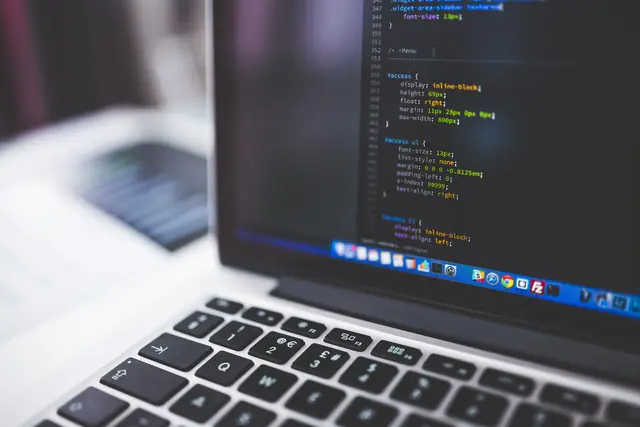 A laptop screen displaying source code in a programming editor.
