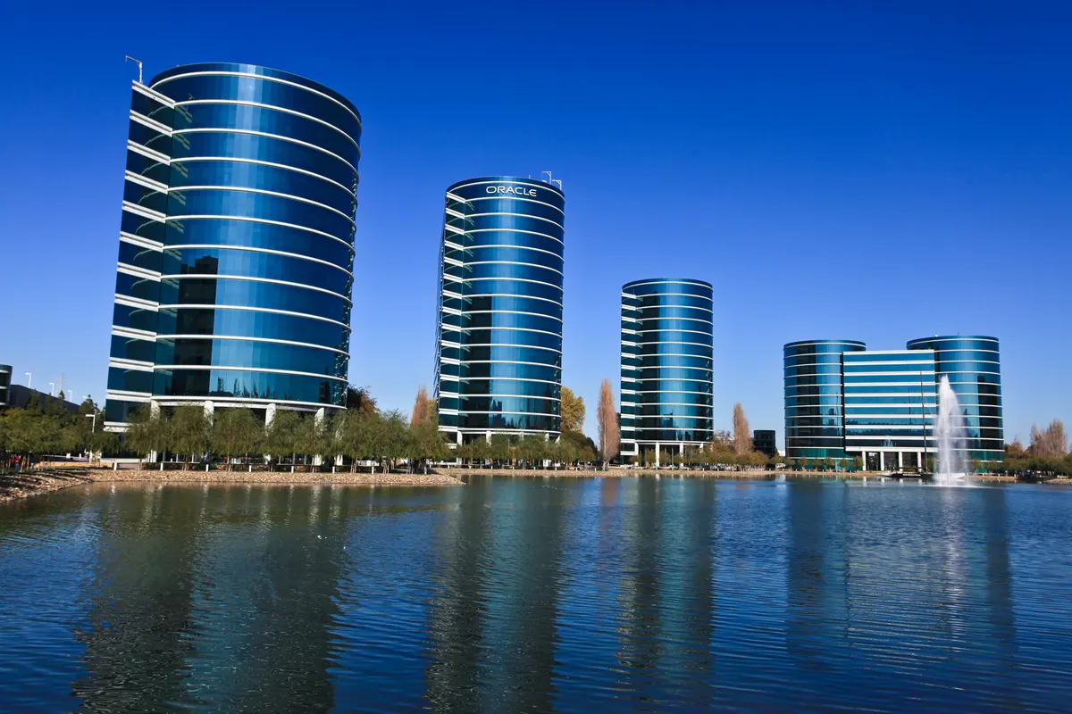 Curved glass office towers reflected in water at Oracle’s Redwood Shores campus.