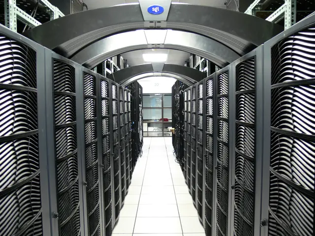 Rows of black equipment cabinets beneath curved overhead supports in a data center.