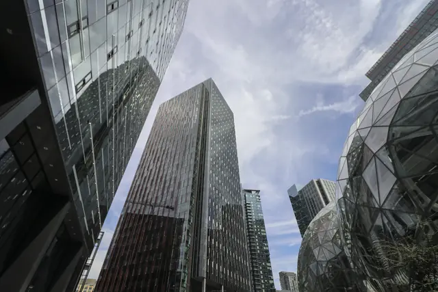 Glass office towers and the edge of Amazon’s glass Spheres beneath a cloudy sky.