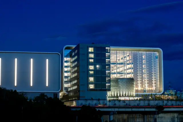 An illuminated semiconductor research building with tall vertical lights at night.