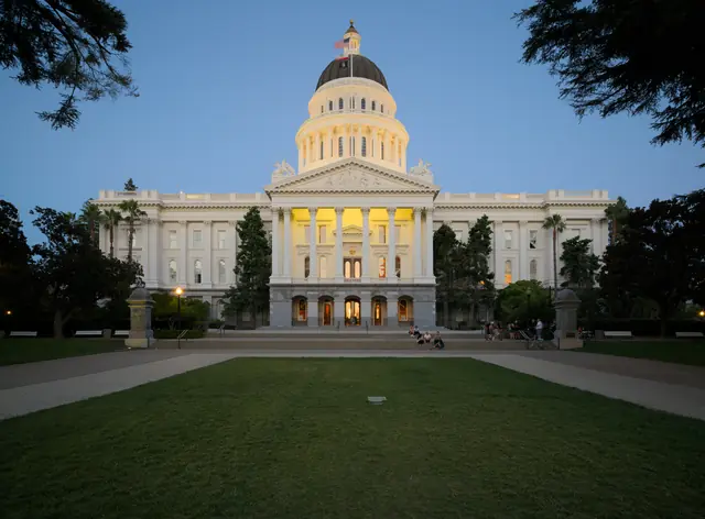 The illuminated California State Capitol beneath a blue evening sky.