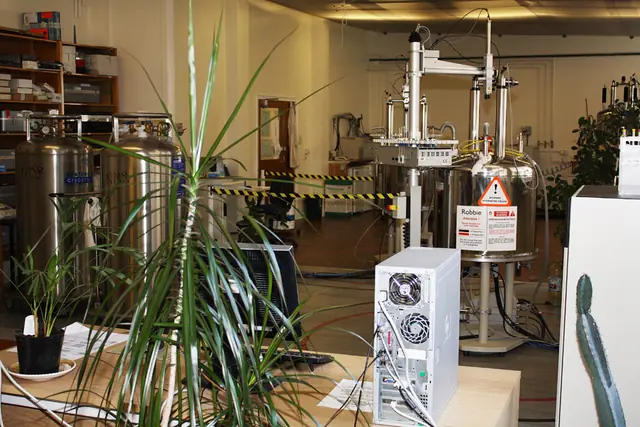 A tall magnetic resonance instrument surrounded by tubing and laboratory equipment.