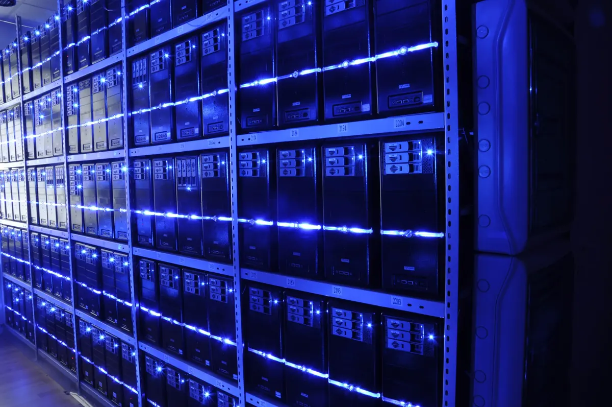 Blue-lit rows of server equipment behind glass-fronted cabinets.