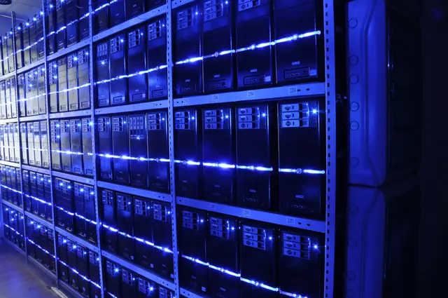 Blue-lit rows of server equipment behind glass-fronted cabinets.