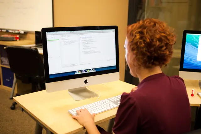A programmer seated at a desk with source code and tests on multiple monitors.
