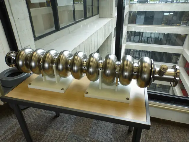 A polished metal nine-cell radio-frequency cavity resting on a display stand.