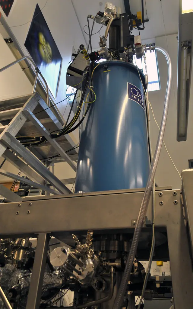 A tall scanning tunneling microscope enclosed by metal supports and vacuum hardware.