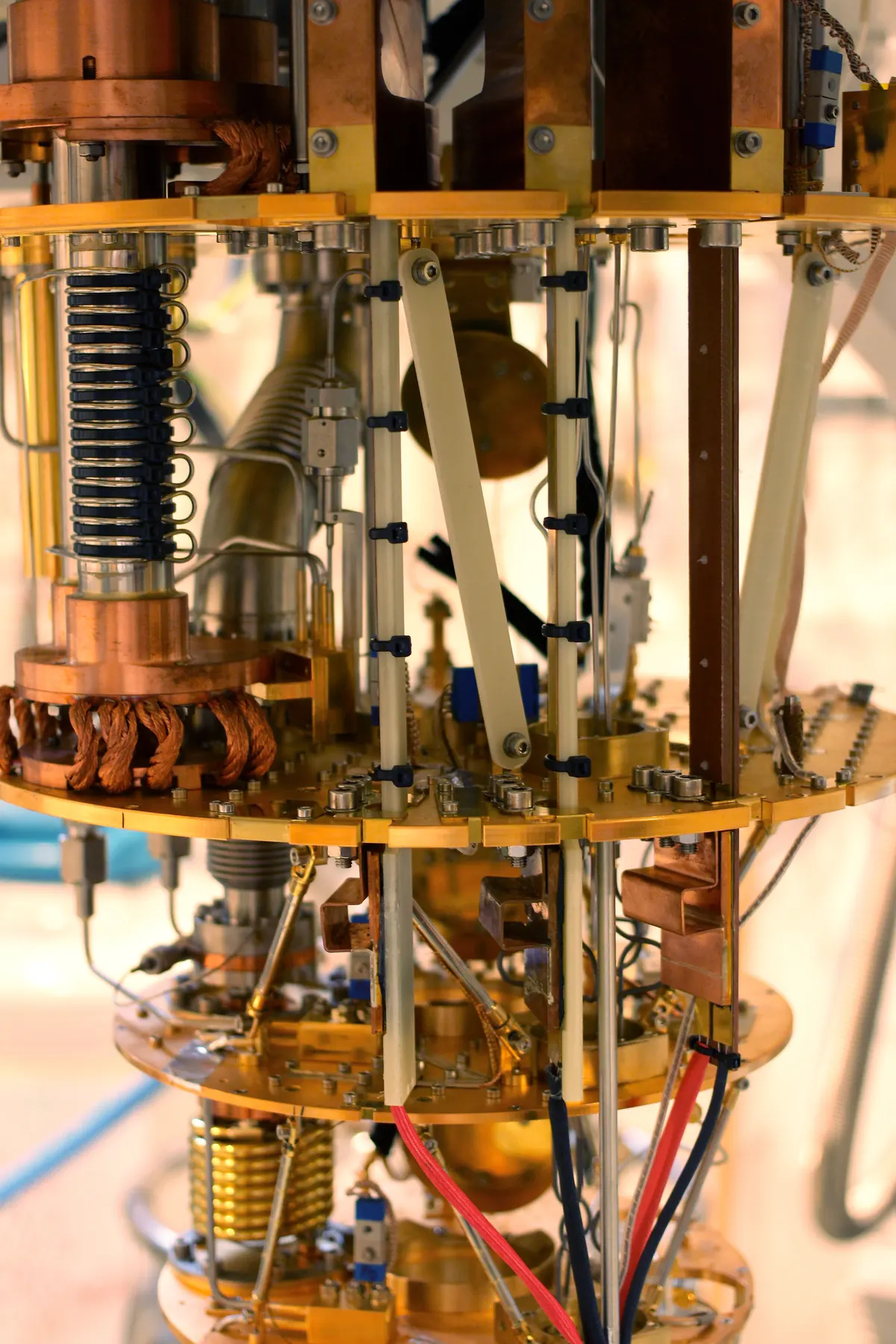 Copper-colored plates and fine wiring inside a tall dilution refrigerator.