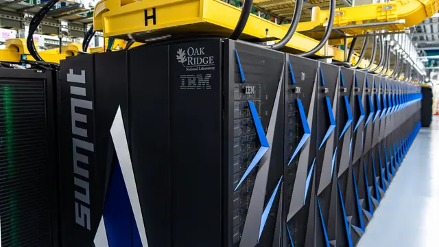 A long row of Summit supercomputer cabinets beneath yellow cable supports.