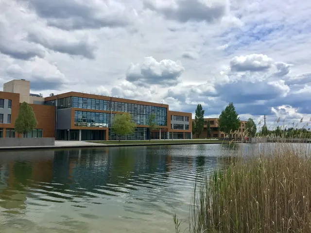 Glass-fronted Infineon office buildings reflected in a landscaped pond.