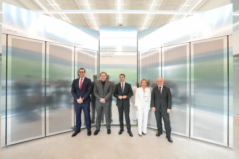 Five people stand in front of tall metallic IBM Quantum System Two enclosures.