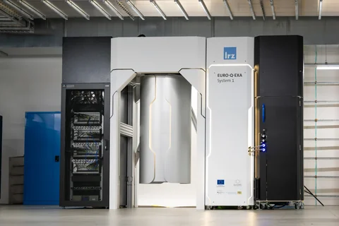 A tall pale equipment enclosure stands between black racks in an industrial computing-room interior.