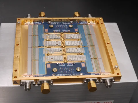 A gold rectangular frame surrounds a blue circuit board and pale rectangular sensor sections, with connectors around the gray mounting plate.