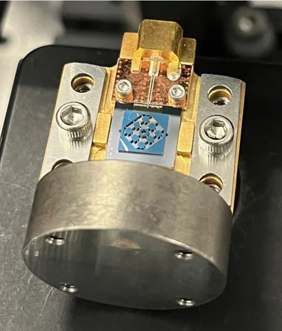 A blue square patterned component sits among gold and silver metal fittings, screws and a rounded metal mount.
