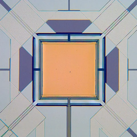 An orange square is surrounded by narrow rectangular borders and fine lines extending toward its corners.