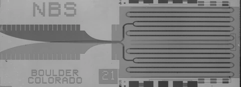 Grayscale chip micrograph with NBS and Boulder Colorado markings, a tapered feed on the left, and four long meandering junction chains on the right.