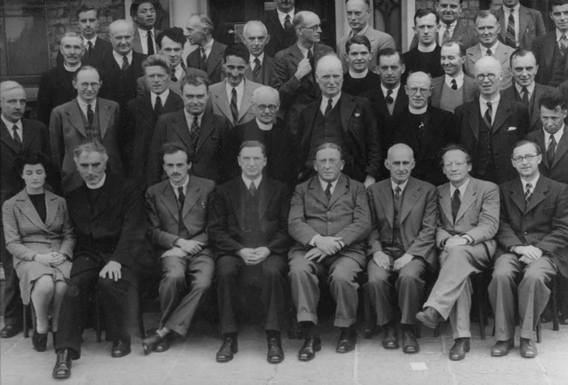 An archival group photograph of scientists on steps in Dublin in 1942; Schrödinger sits second from the right in the front row.
