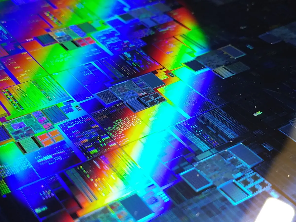 A circular silicon wafer reflecting bands of color.