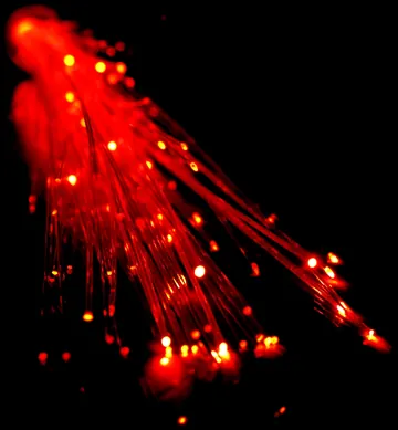Fine optical fibers illuminated red against a dark background.