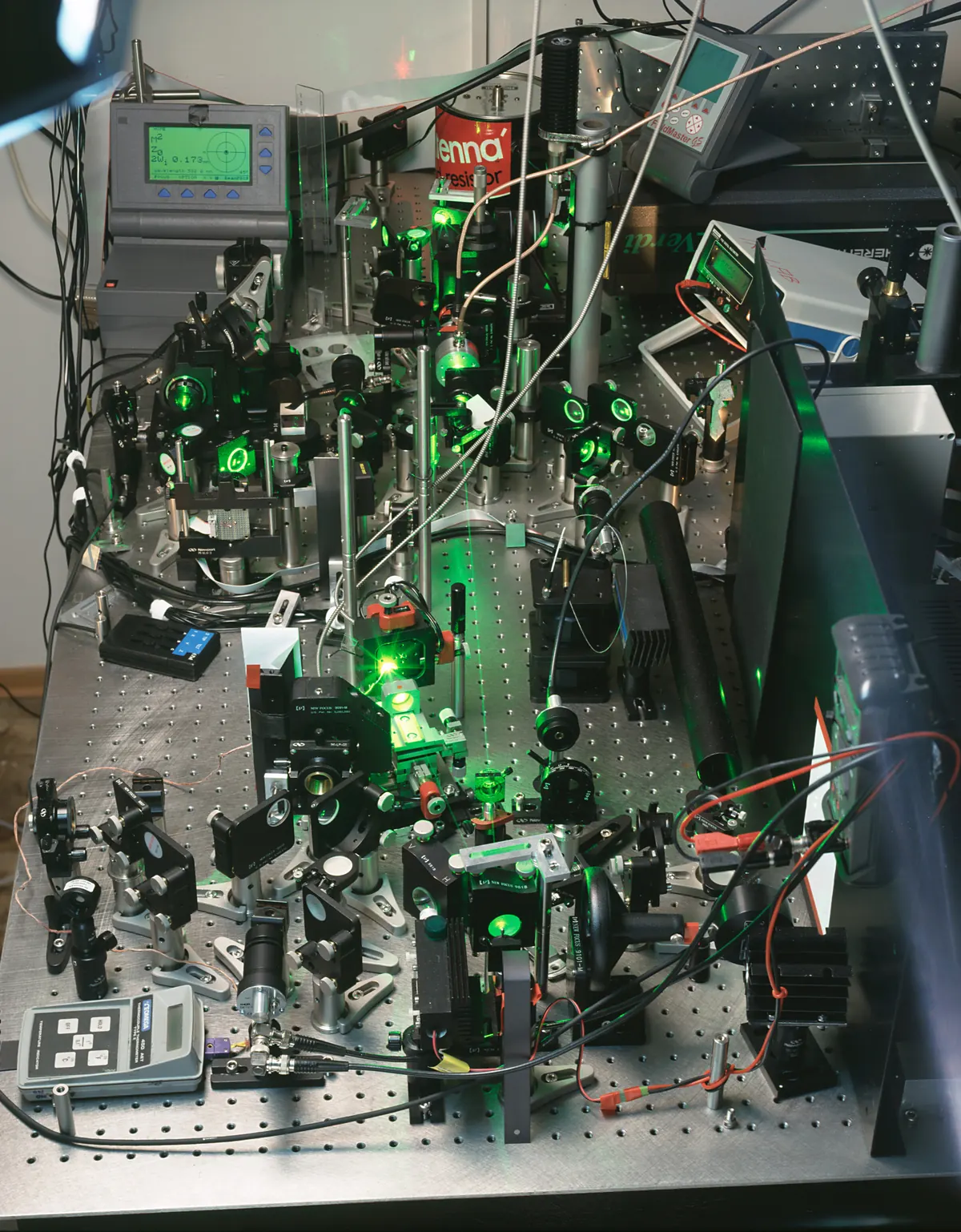 Laser optics, mirrors, cables and mounts arranged on a laboratory optical table.
